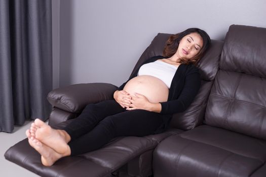 Pregnant woman sleeping on sofa in home