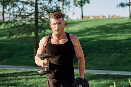 pumped up sports Vykhino in the park with dumbbell workout. High quality photo