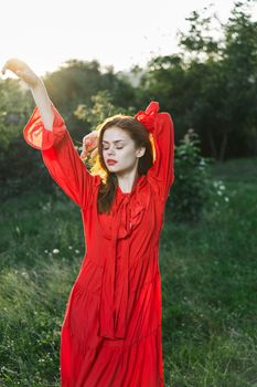 attractive woman in red dress posing in nature green grass. High quality photo