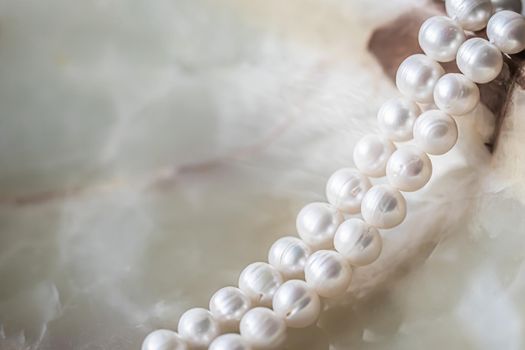 Nature white string of pearls on marble background in soft focus, with highlights.