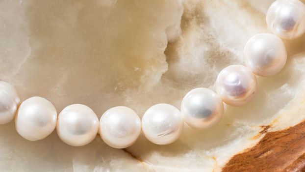 Nature white string of pearls on marble background in soft focus, with highlights