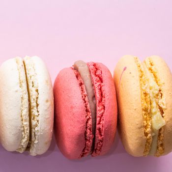 Colorful french cookies macarons set on pink background. Tasty fruit, almond sweet cookies, cake macaron. Holiday backdrop design.