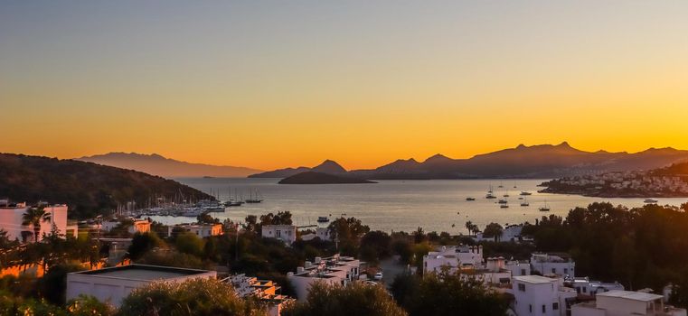 Bright colorful sunset in the beautiful bay of the Aegean sea with islands, mountains and boats. Summer holiday concept and travel background