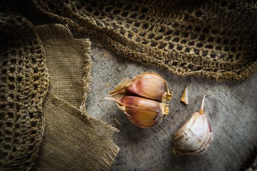 Garlic cloves and natural linen napkin on rustic wooden background