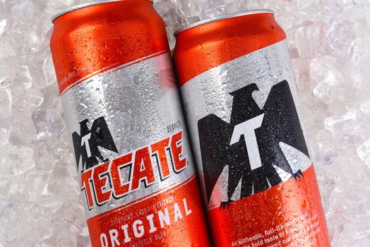 IRVINE, CALIFORNIA - MARCH 21, 2018: Two Tecate Original Cerveza cans on ice closeup. Cuauhtemoc Moctezuma Brewery is a major brewer based in Monterrey, Nuevo Leon, Mexico, founded in 1890.