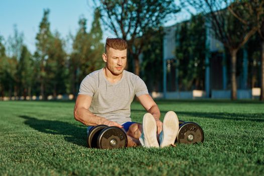 athletic man with dumbbells in the park exercise motivation. High quality photo
