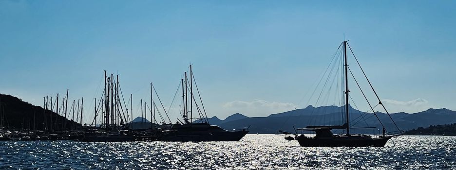 Tranquil seascape and coastal nature concept. Sea, boats, mountains and blue sky over horizon at sunset.