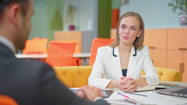 Beautiful girl interviewing employee. Close-up of two business people sitting in the workplace with documents on the table. Successful interview with a supervisor and employee.