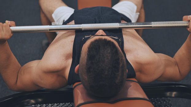 An Arab man shakes his chest with a barbell lying down