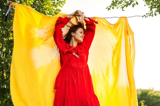 beautiful woman posing in red dress outdoors yellow cloth. High quality photo