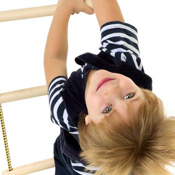 Cute little boy climbing rope ladder. Top view of kid wearing casual clothes having fun on isolated white background in studio. Active healthy lifestyle and leisure concept