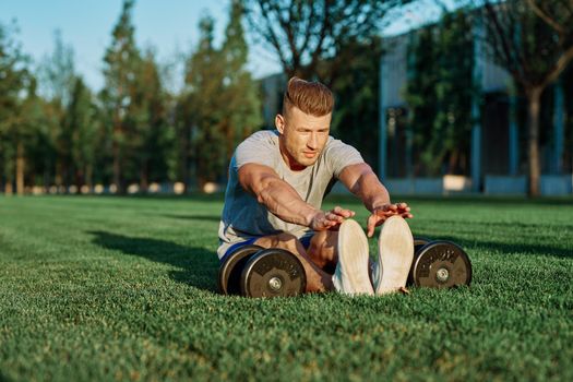 athletic man with dumbbells in the park exercise motivation. High quality photo