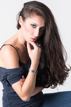 Brunette woman with blue eyes wearing sweater and blue jeans on white background. Studio shoot