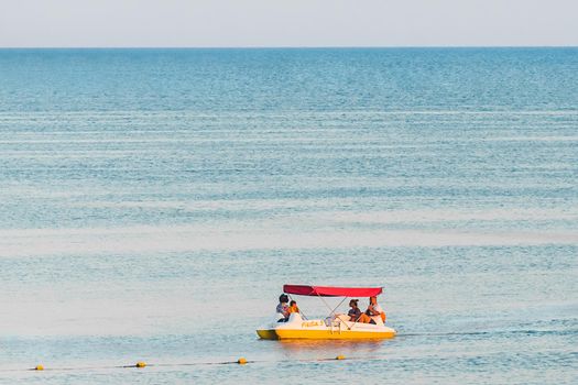 Ukraine, Iron Port - August 22, 2020: Tourists group swim on a pedal boat on the background of the sea near the shore.