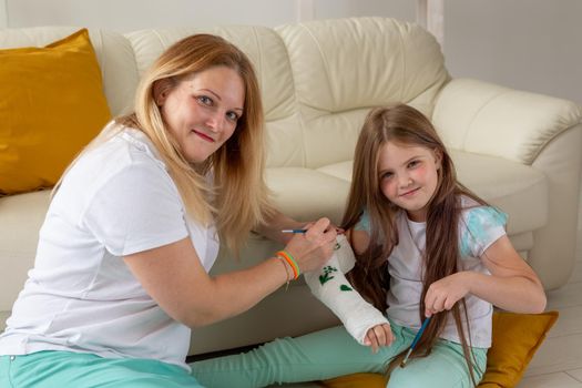 Mother and daughter drawing picture on bandage using paints. Play therapy concept