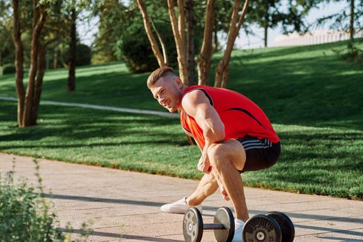 sporty man in the morning in the park with dumbbells exercise. High quality photo