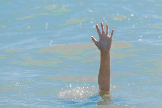 A hand from under the water of a drowning girl, help and urgent rescue of a person during a dangerous swimming, sos.