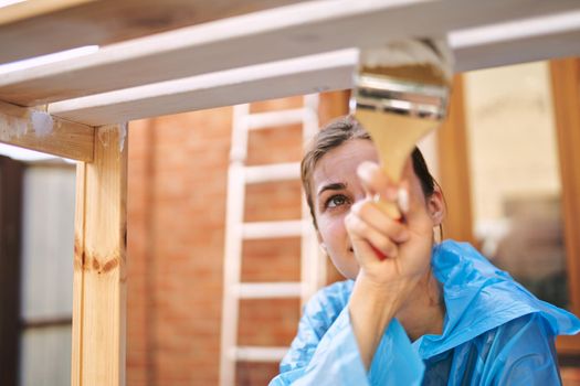 a painter with a brush in his hands paints wooden objects repairing fittings. High quality photo