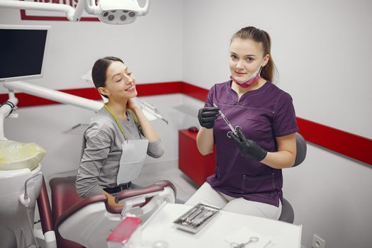 Beautiful lady in the dentist's office. Woman in a purple uniform