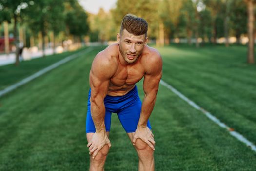 sporty man with pumped up body in park workout exercise. High quality photo