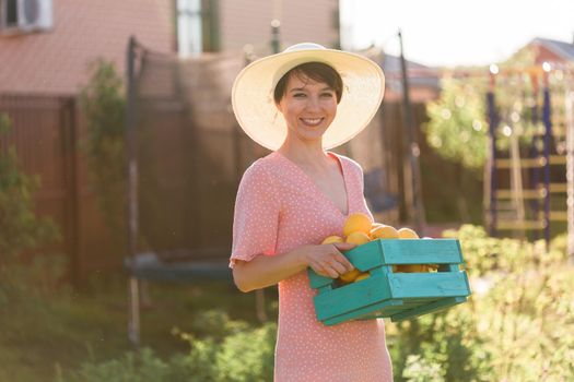 Woman holding wooden crate with fresh organic lemons from farm. Harvest, autumn season and farming.