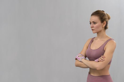 Warming up stretching folded arms young woman exercising at home with wearing pink outfit. Sport and recreation concept. Pensive girl is enjoying with her training process working hard.