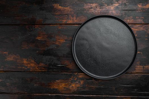 Empty black plate set, on old dark wooden table background