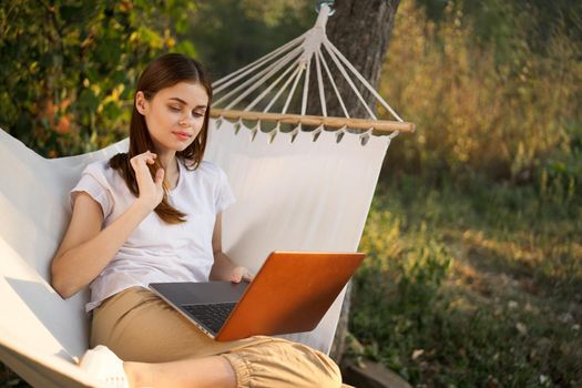 woman working on laptop in nature hammock freelance. High quality photo