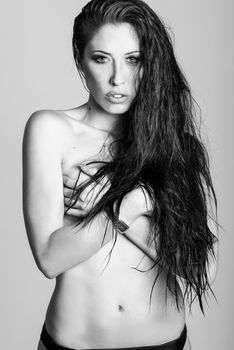 Half naked brunette woman wearing panties with very long curly hair on white background. Studio shot