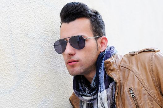 Portrait of a young handsome man, model of fashion, wearing tinted sunglasses