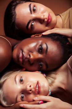 young pretty asian, caucasian, afro woman posing cheerful together on brown background, lifestyle diverse nationality people concept closeup