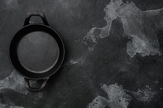 Cast iron frying pan set with copy space for text or food with copy space for text or food, top view flat lay, on black dark stone table background