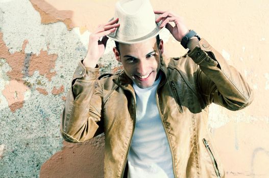 Portrait of a handsome young man smiling with a hat in urban background