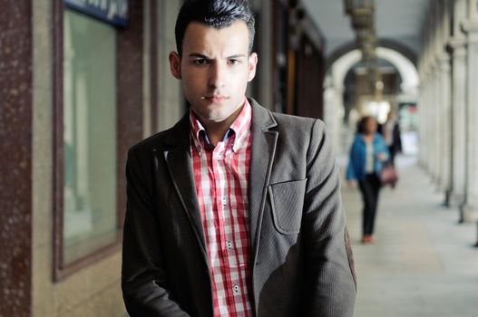 Portrait of a young handsome man, model of fashion, wearing jacket and shirt in urban background