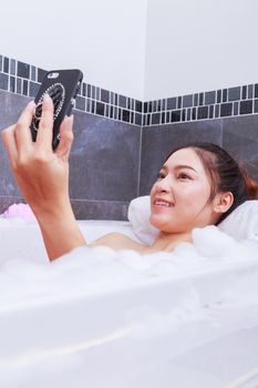 woman making selfie photo in bathtub in the bathroom
