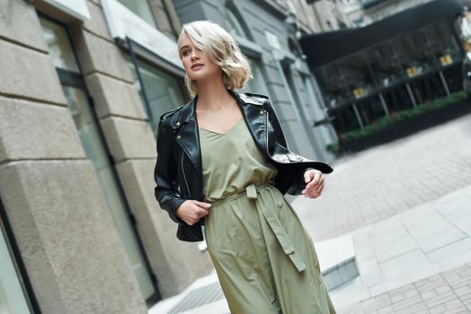 Fashion. Young stylish woman walking on the city street looking aside smiling curious