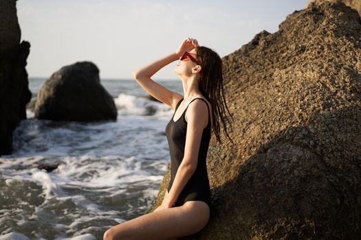 woman in black swimsuit rocks posing oceans. High quality photo