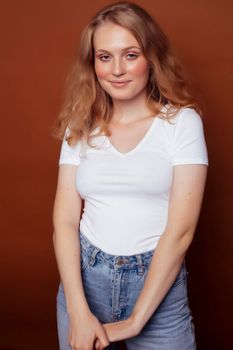 young pretty girl with blond curly hair posing cheerful on brown background, lifestyle people concept close up