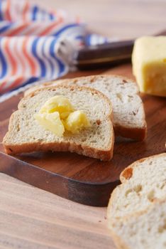 slice of butter and whole meal bread on chopping board .