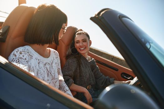 Two happy friends in the cabriolet driving everywhere and looking for freedom and fun