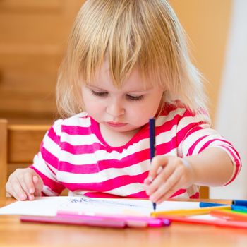 Cute three-year-old girl draws felt-tip pens at home