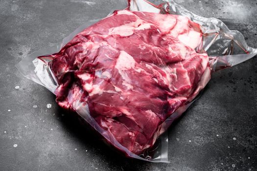 Fresh, raw, vacuum packed cut lamb meat set, on black dark stone table background, with copy space for text