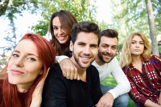 Group of young people together outdoors in urban background. Women and men sitting on stairs in the street wearing casual clothes.