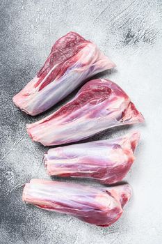 Raw lamb shanks meat on stone table. White background. Top view.