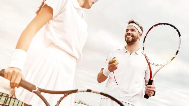 They play like a team. Cropped shot of beautiful young woman and man holding tennis rackets and discussing set