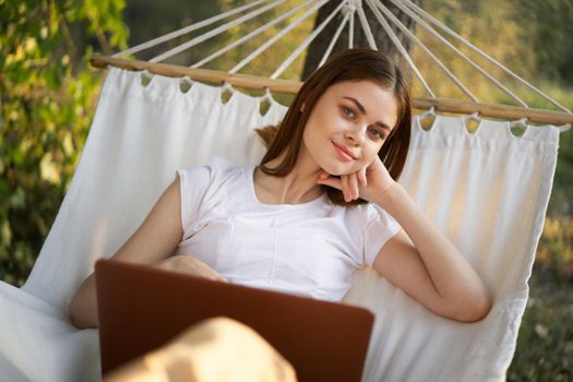 woman working in front of laptop in a hammock in nature. High quality photo