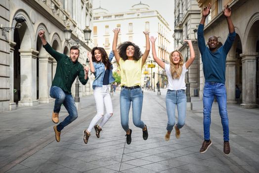 Multi-ethnic group of young people having fun together outdoors in urban background. group of people jumping together