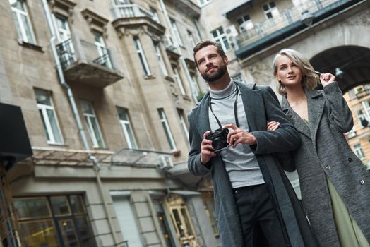 Romantic date outdoors. Young couple walking on the city street taking photos on camera smiling excited