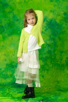 A charming little school girl corrects her long silky hair with her hands. The concept of style and fashion, happy people.