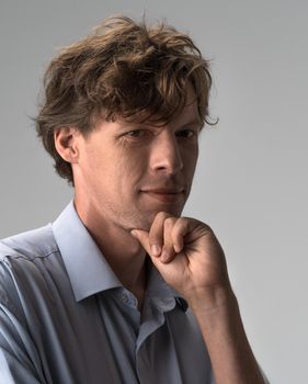 Thoughtful guy leaning hand, rubbing beard while thinking over difficult choice, indoor studio shot isolated on white or light grey background. Facial expressions, emotions, feelings.